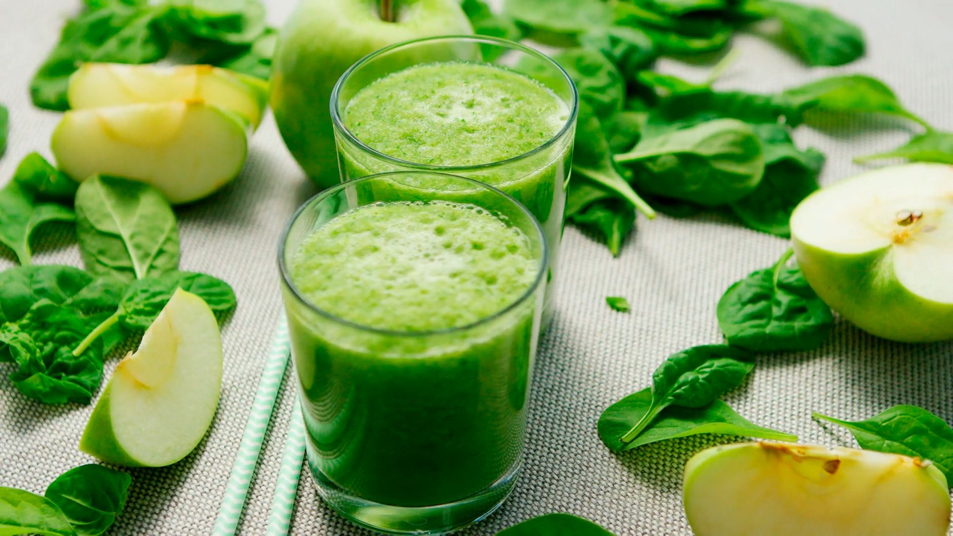 Copo de suco verde detox cercado de folhas e maçã