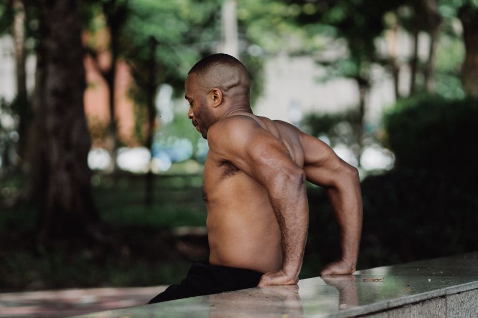 Homem fazendo paralelas em barras de treino ao ar livre