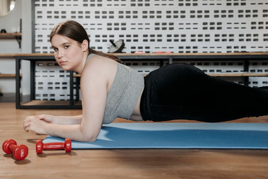 Mulher fazendo prancha sobre um tapete de exercícios em casa
