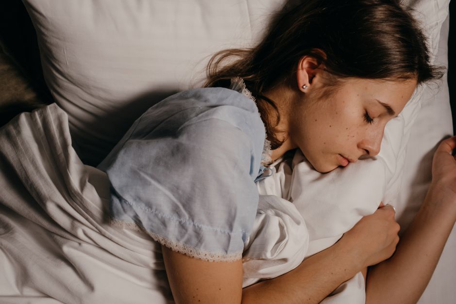 Mulher dormindo tranquilamente em um travesseiro branco à noite